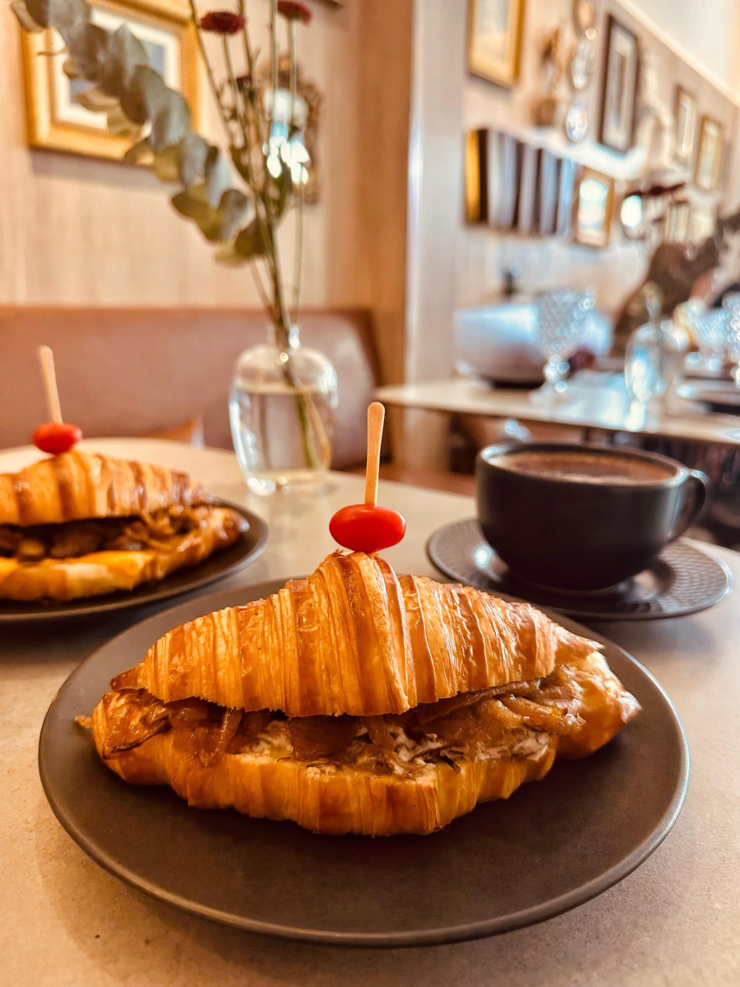 Croissant recheado com cebola caramelizada ao lado de uma xícara de cappuccino