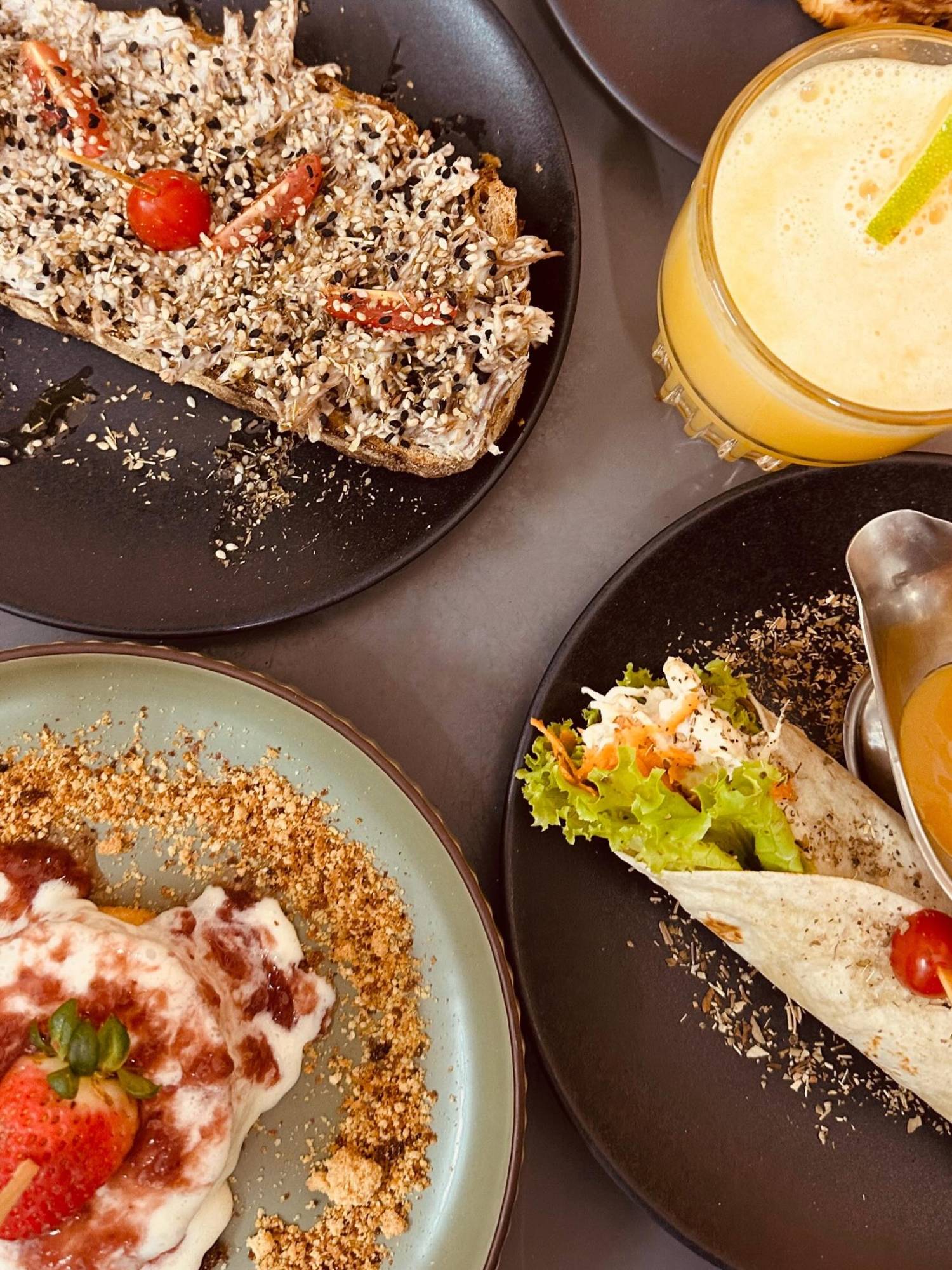 Mesa vista de cima com bruschetta, wrap, suco e sobremesa de morango